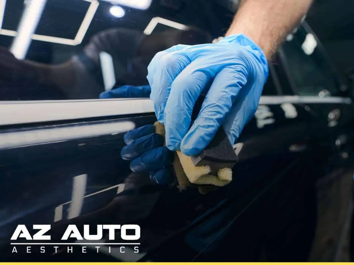 Application of ceramic coating on a car door by a professional wearing gloves